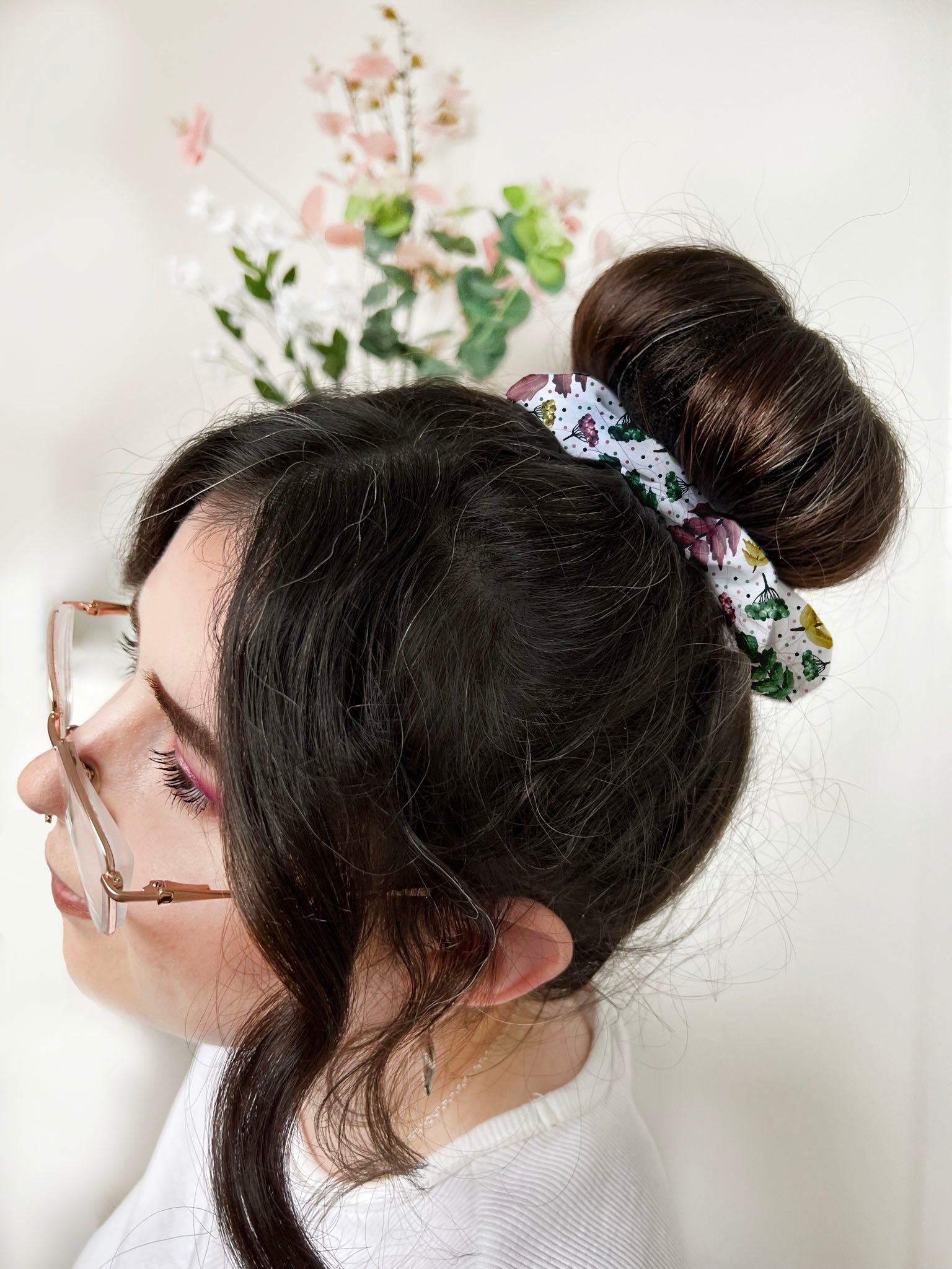 pretty foliage patterned scrunchie on a bun of a dark haired girl with glasses